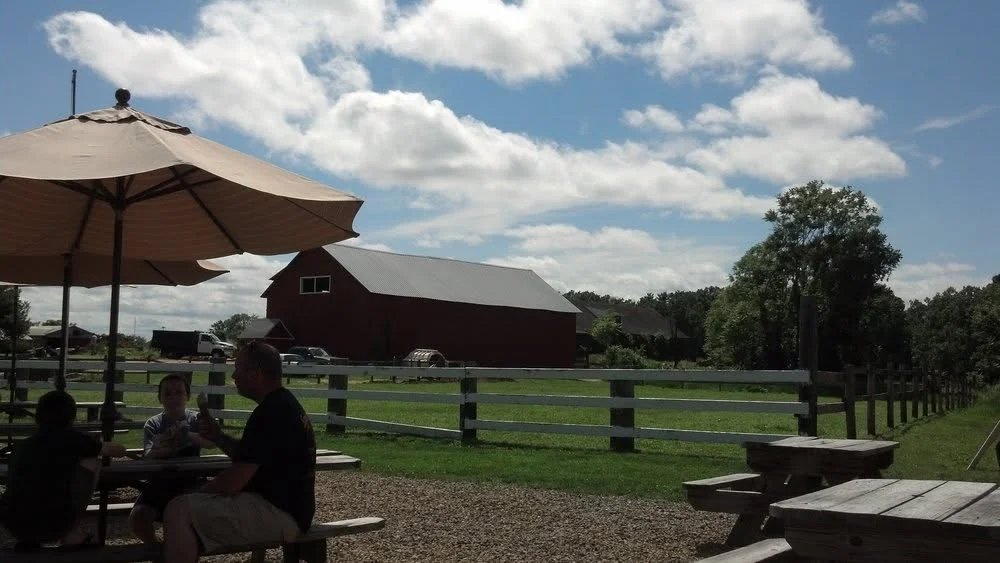 Families eating ice cream at picnic tables in front of the red barn