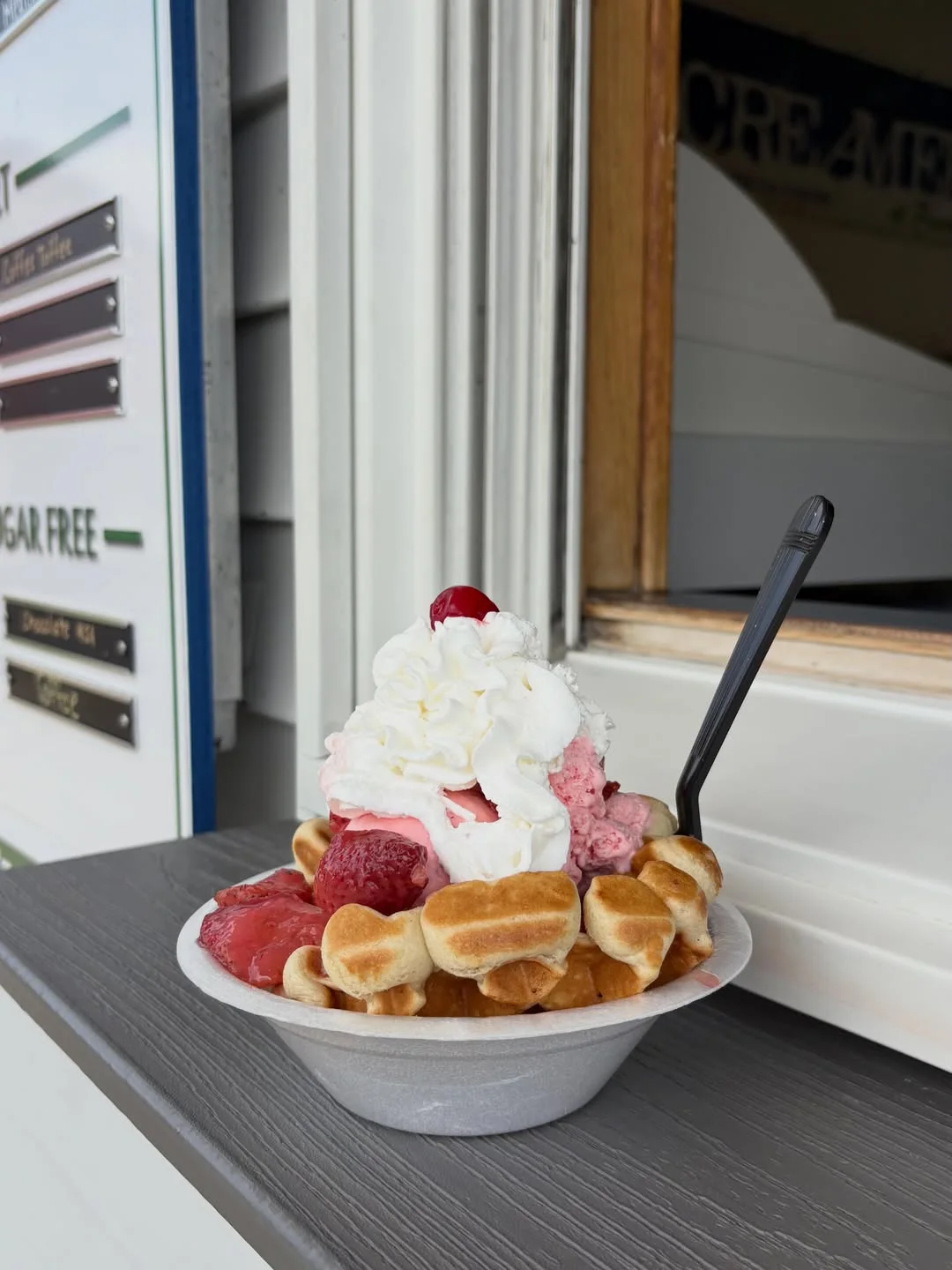A strawberry waffle sundae piled with whipped cream at the window